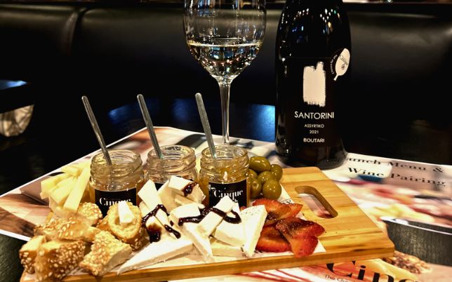 Greek wine and food pairing in Athens with cheese olives chutneys and Santorini wine